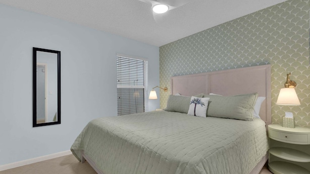 A bedroom with a bed, bedside lamps, a mirror, and a window with blinds.