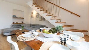 A modern living room with a staircase, a dining area with a wooden table, and a grey sofa. - Amazing home in Porec (Porec)