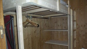 Ett rum med träpanel, en våningssäng, en trägalge och ett metallställ.