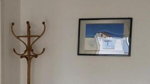 Ein weißes Sofa mit zwei braunen Kissen, ein Holz-Kleiderständer und ein gerahmtes Bild an der Wand.