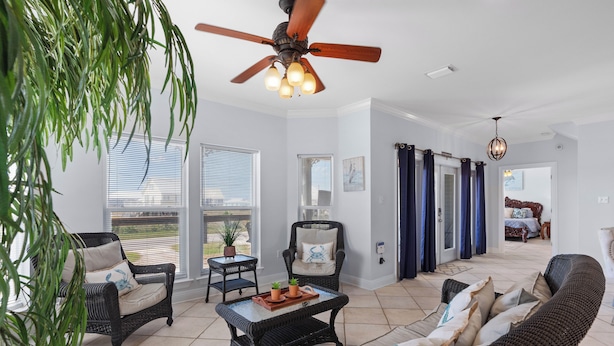 A spacious living room with wicker furniture, a ceiling fan, and a view through the glass doors.