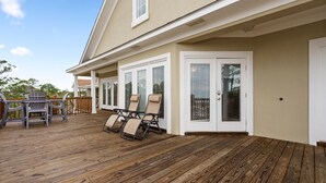 Eine überdachte Terrasse mit Holzboden und Gartenmöbeln, darunter Stühle und ein Tisch.
