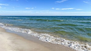 A beach with clear blue water and a sandy shore. - Dauphin Tale - Family Friendly Gulf View Home only Steps to Gulf of Mexico (Dauphin Island)