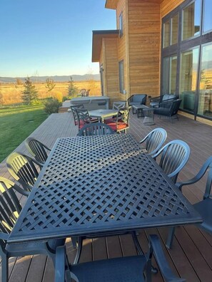 Eine Terrasse mit Tisch und Stühlen, mit Blick auf ein saftiges Grasfeld und Berge.