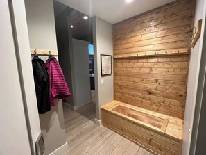 A hallway with a wooden bench, coat hooks with jackets, and a framed map on the wall. - Indoor/Outdoor Living with 4-Peak Teton View (Driggs)