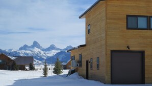 A wooden building with a garage, surrounded by snow and mountains in the background. - Indoor/Outdoor Living with 4-Peak Teton View (Driggs)
