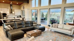 A spacious living room with a sectional sofa, a white armchair, and a coffee table. - Indoor/Outdoor Living with 4-Peak Teton View (Driggs)
