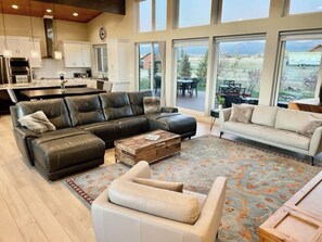A spacious living room with a sectional sofa, a white armchair, and a coffee table.