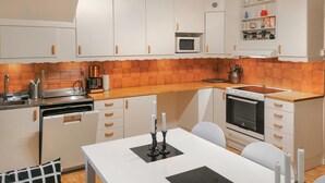 Una cocina compacta con gabinetes blancos, un microondas, una estufa y un lavabo.