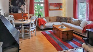 Una sala de estar moderna con comedor, un conjunto de sofás, una mesa de centro de madera y un cuadro en la pared.