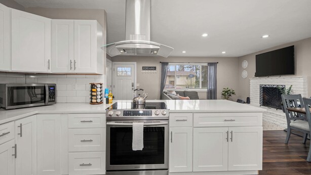 Una cocina moderna con armarios blancos, estufa de acero inoxidable y horno.