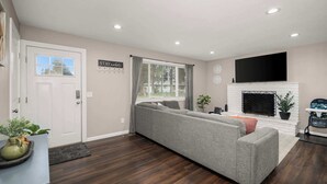 Una sala de estar con un sofá modular, una chimenea y un televisor de pantalla plana.