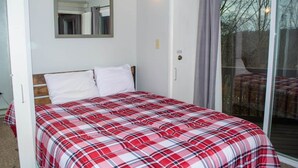Une chambre avec un lit, un miroir, une porte-fenêtre coulissante et une vue sur l’extérieur.