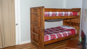 A bunk bed with a plaid bedspread, a wooden desk, and a television. - Winterplace E102 Ski in Ski out First Floor (Ghent)