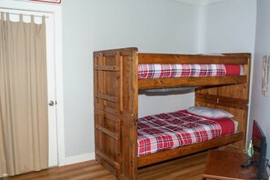 A bunk bed with a plaid bedspread, a wooden desk, and a television. - Winterplace E102 Ski in Ski out First Floor (Ghent)