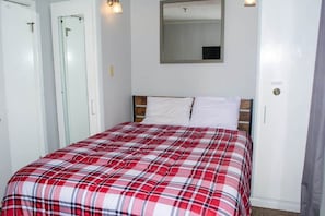 A bedroom with a bed, a mirror, and a door.