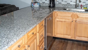 Una cucina con mobili in legno, un piano di lavoro in granito, una macchina da caffè e un lavello.
