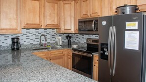 Una cucina con mobili in legno, un frigorifero in acciaio inox, un forno a microonde, un forno e una macchina da caffè.