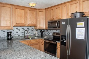 A kitchen with wooden cabinets, a stainless steel refrigerator, a microwave, an oven, and a coffee maker. - Winterplace E103 Ski in Ski out condo First floor (Ghent)