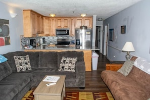 A compact living space with a kitchenette, a gray sofa, a brown sofa, and a wooden coffee table. - Winterplace E103 Ski in Ski out condo First floor (Ghent)