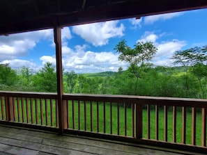 A wooden deck with a view of a green landscape and trees under a clear sky. - Winterplace E104 Ski in Ski out condo First floor (Ghent)