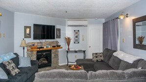 Ein Wohnzimmer mit Kamin, Fernseher und einer Couch.