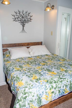 A bedroom with a bed, a wall-mounted light fixture, and a door.