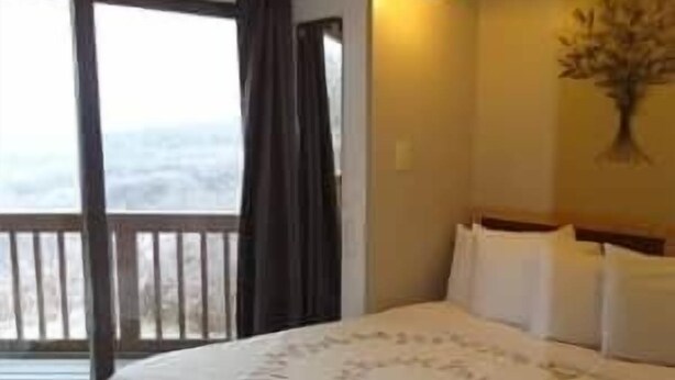 Ein Hotelzimmer mit Bett, einer Schiebetür zum Außenbereich und einer Wandleuchte.
