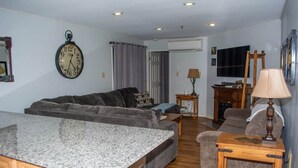 Un salon avec un canapé, une table basse, une lampe, une horloge et un téléviseur.