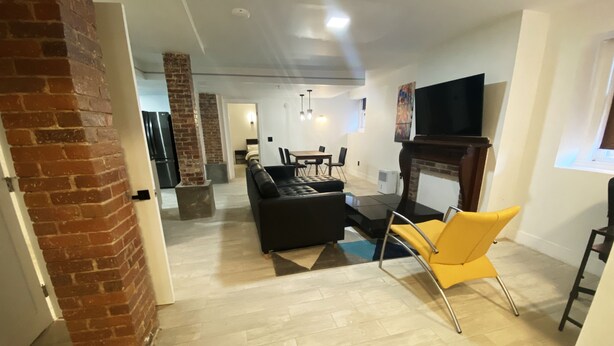 A modern living room with a fireplace, a sofa, a yellow chair, and a TV. - Ultra cool new modern flat (Portland)