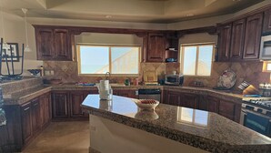 A kitchen with granite countertops, wooden cabinets, a built-in oven, and a large window providing natural light.