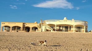 A large, circular building with a dome on top, surrounded by a sandy beach.