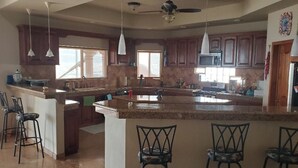 A spacious kitchen with a large island, bar stools, and pendant lighting.