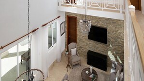 Un espacio habitable amplio con chimenea, techo alto y balcón con barandilla.