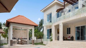 Una casa moderna de dos pisos con piscina, zona de estar al aire libre y un porche cubierto.