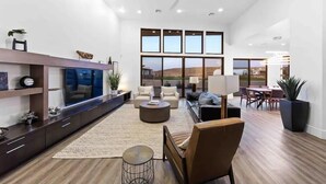 A spacious living room with a large TV, comfortable seating, and a view of the outdoors.