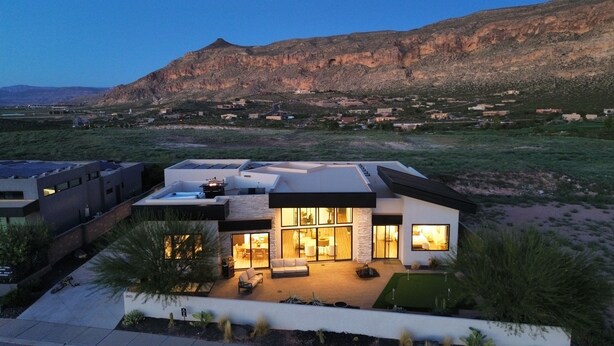 A modern house with a flat roof, large windows, and a patio area.