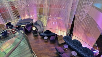 A modern interior with a glass railing, seating areas, and a view of the cityscape.
