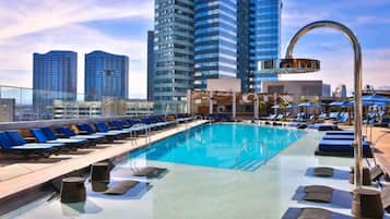 A rooftop pool with sun loungers and a view of tall buildings.