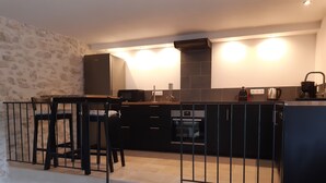 Eine Küche mit einer Steinwand, einer schwarzen Arbeitsplatte, einer Mikrowelle, einem Backofen und einer Kaffeemaschine.