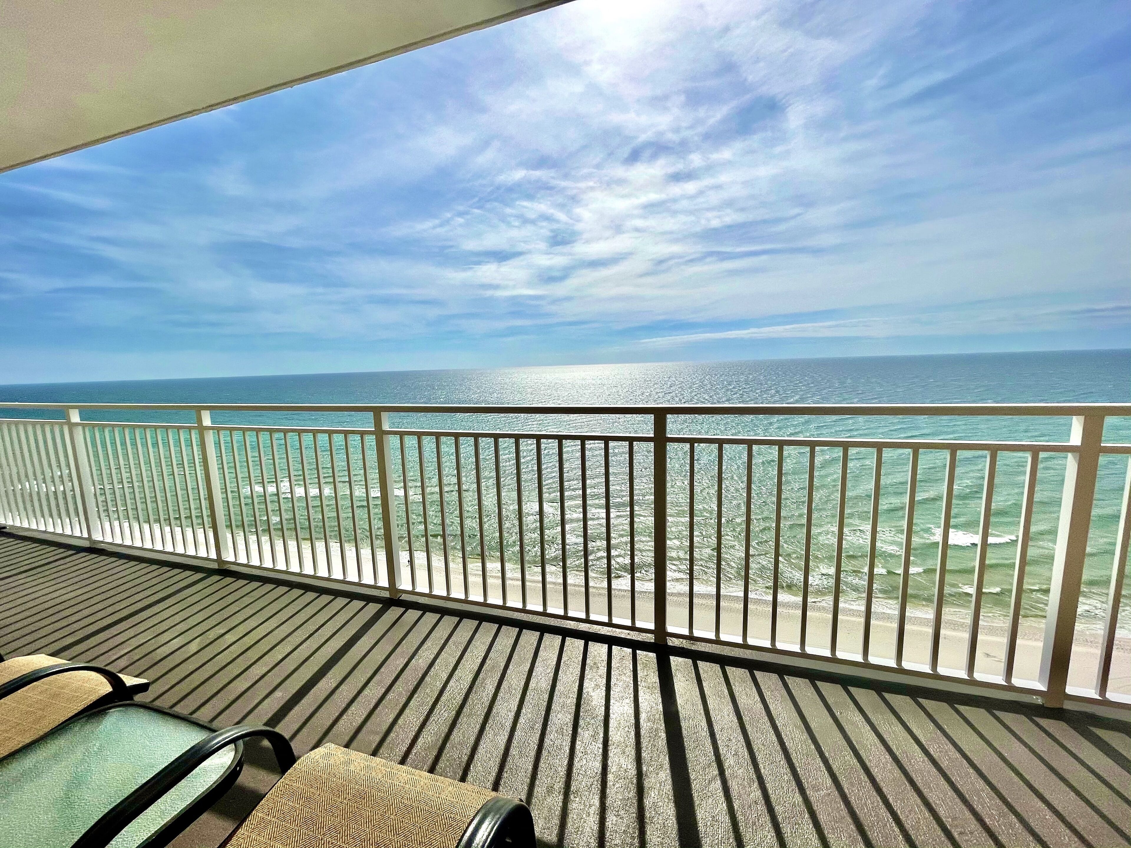 A balcony with a view of the ocean, featuring a railing and seating area.