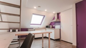 A modern kitchen with a skylight, white cabinets, and a purple accent wall.