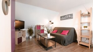 A modern living room with a sofa, coffee table, TV, storage units, and a bookshelf.
