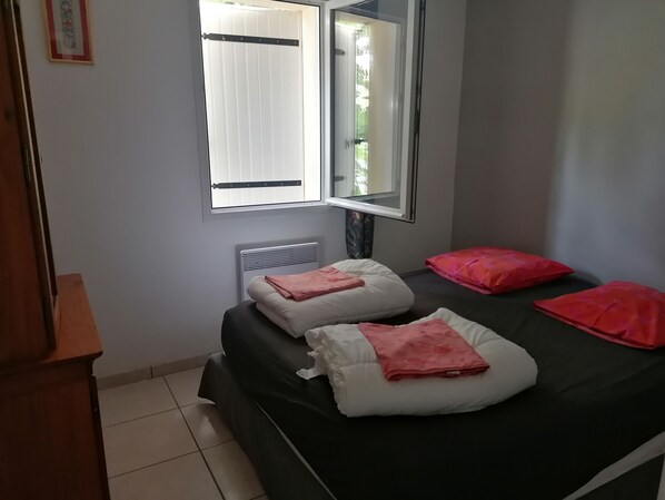 A bedroom with a bed, a radiator, a window, and a mirror.