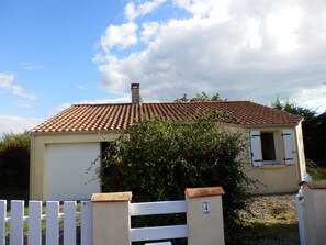 Una casa con techo de tejas, cerca blanca y un cartel con el número 4.