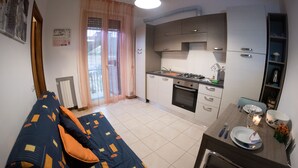 Un espace de vie compact comprenant un canapé, une table à manger et un coin cuisine.