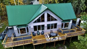 A large house with a green roof, multiple decks, and outdoor seating areas.