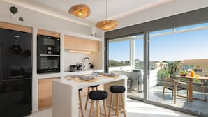 Une cuisine moderne dotée d’un îlot central, de tabourets de bar et d’un coin repas offrant une vue agréable.