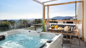 Une terrasse sur le toit avec un jacuzzi, un coin salon et une table avec des boissons.