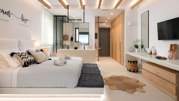 Une chambre moderne avec un grand lit, des tables de chevet, une télévision et un miroir.